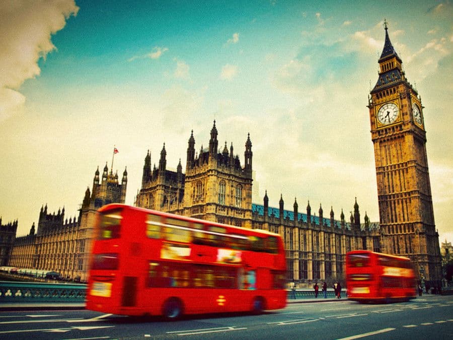 Red London buses passing Big Ben and the Houses of Parliament
