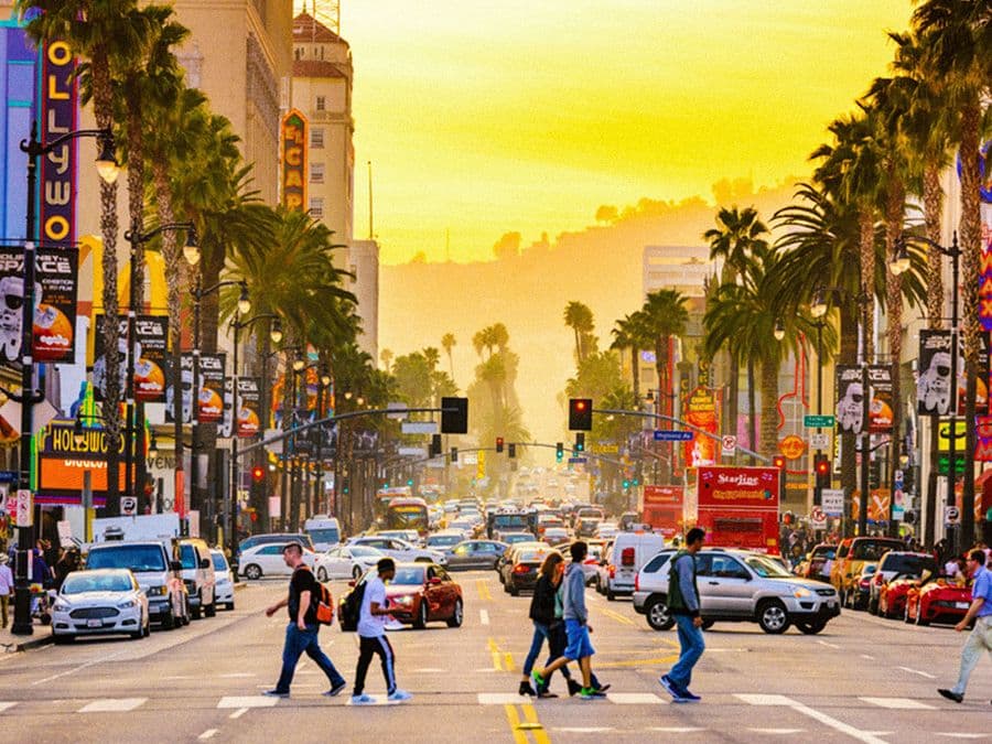 Hollywood Boulevard at sunset with palm trees and pedestrians crossing