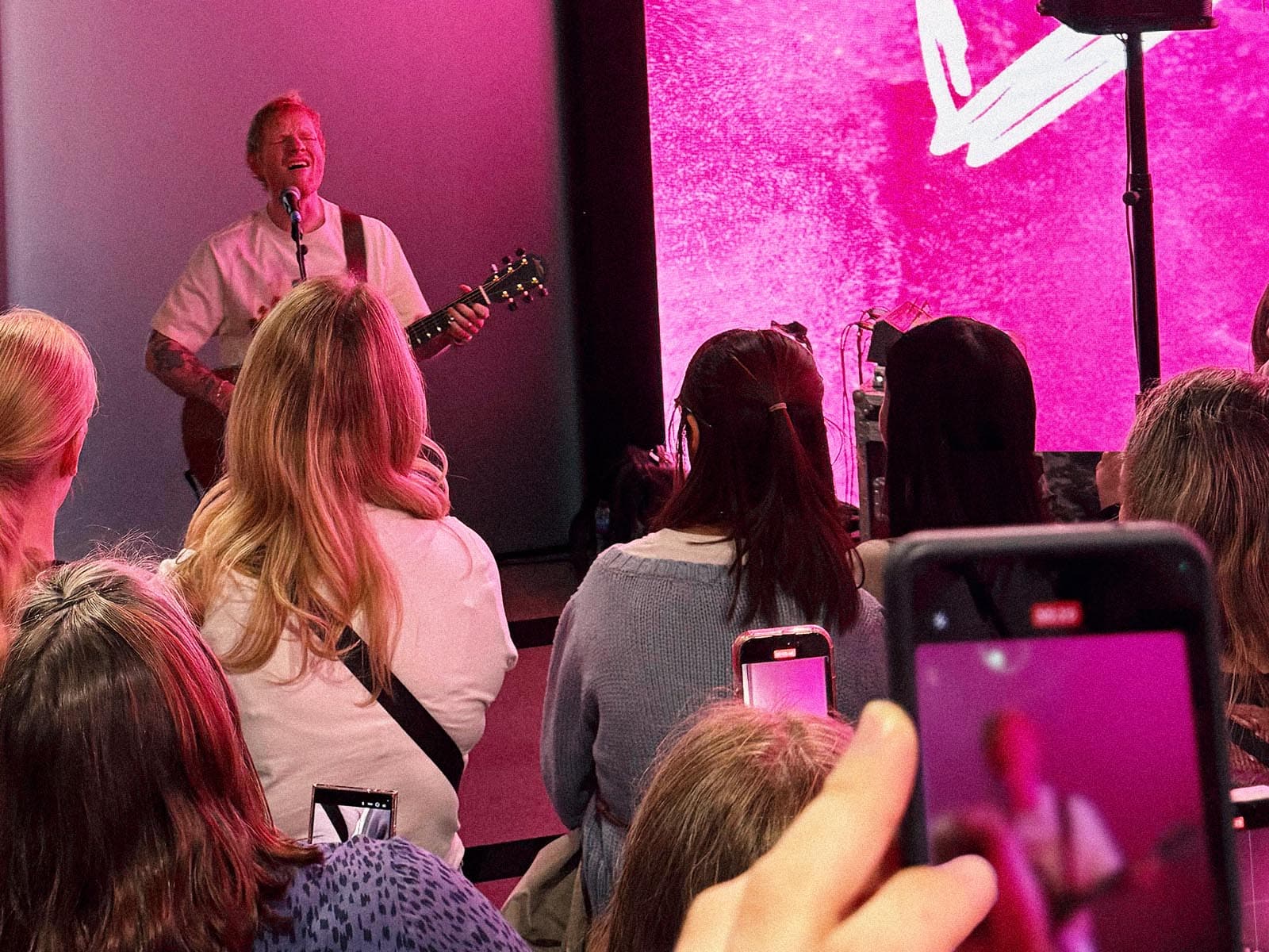 Fans filming an in-store acoustic performance at an album launch